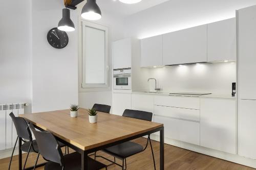 una cocina con armarios blancos y una mesa y sillas de madera. en Always Easy I Zurriola, en San Sebastián