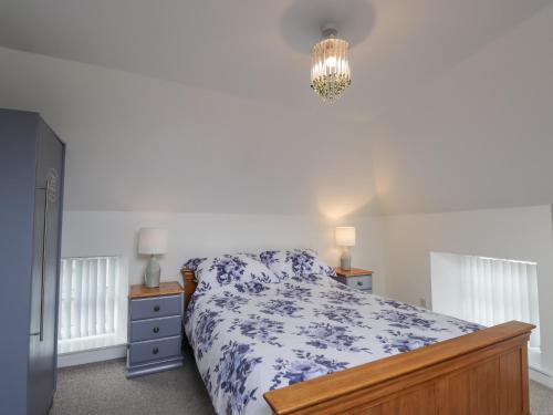 a bedroom with a bed and two night stands and a chandelier at Meredith Cottage in Banff