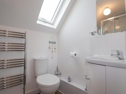 a white bathroom with a toilet and a sink at Meredith Cottage in Banff