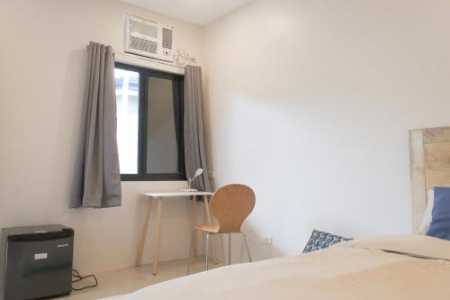 een slaapkamer met een bed, een stoel en een raam bij Sandy Home in Baler
