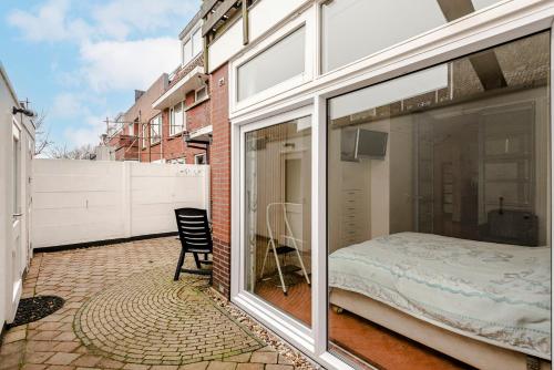 een kamer met glazen schuifdeuren en een bed op een balkon bij Casa Queensway in Zandvoort