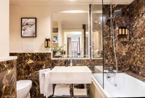 a bathroom with a sink and a tub and a toilet at Nerva Boutique Hotel in Rome
