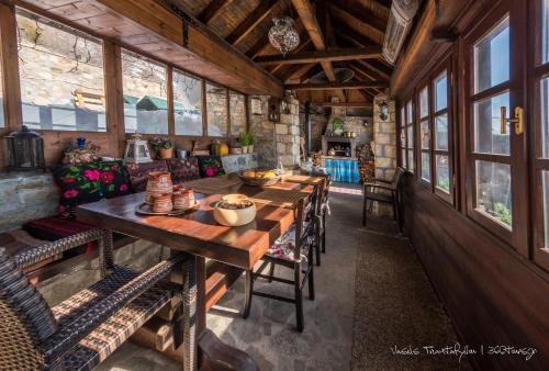 une salle à manger avec une longue table et quelques fenêtres dans l'établissement Argyro Guesthouse - Ξενώνας Αργυρώ, à Nymfaio