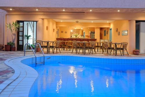 a pool with chairs and a table and a dining room at Cleopatra Apartments in Hersonissos