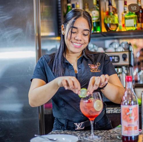 a woman making a drink at a bar at Playa Palmera Beach Resort in Punta Cana