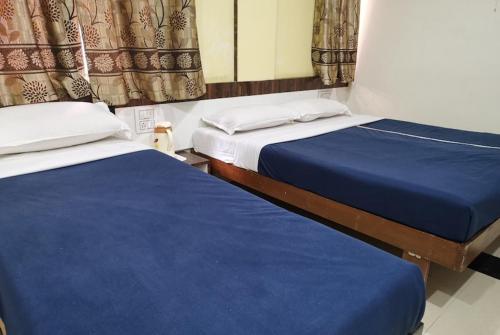 two beds in a room with blue sheets at Hotel Royal Treat in Kolhapur