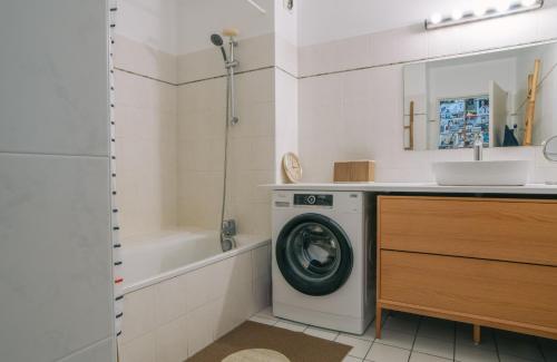 een badkamer met een wasmachine en een wastafel bij Chiberta - entre plages et golf in Anglet