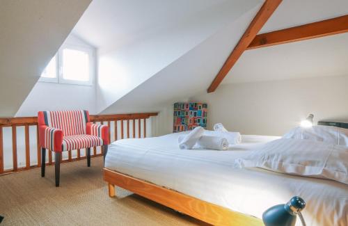 een slaapkamer met een bed en een stoel op zolder bij Chiberta - entre plages et golf in Anglet