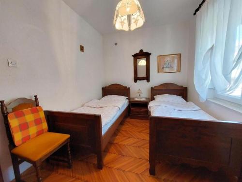 two beds in a room with a chair and a window at Apartment Durda in Senj