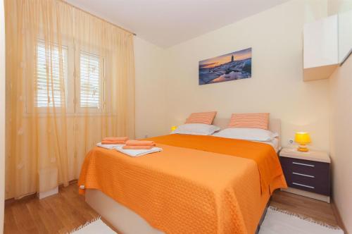 a bedroom with a bed with an orange blanket at Apartment Temza in Krilo