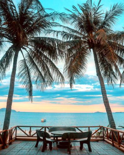 two palm trees and a picnic table on the beach at Paradise Resort Doc Let - All Inclusive in Doc Let