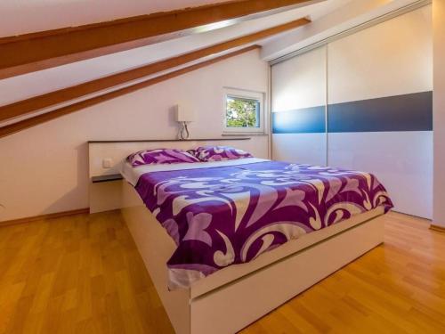 a bedroom with a bed with a purple comforter at Apartments Sylvia in Dramalj