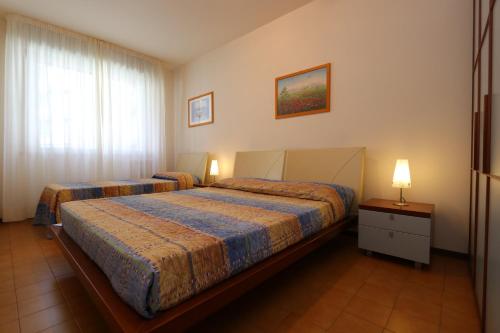 a bedroom with two beds and a window and two lamps at Appartamenti Erica in Bibione
