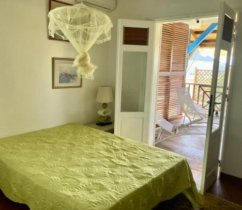 een slaapkamer met een groen bed en een balkon bij Chambre chez l'habitant à L' Amirade chez Michelle in Grande Anse