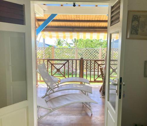 a door leading to a patio with a chair on a porch at Chambre chez l'habitant à L' Amirade chez Michelle in Grande Anse