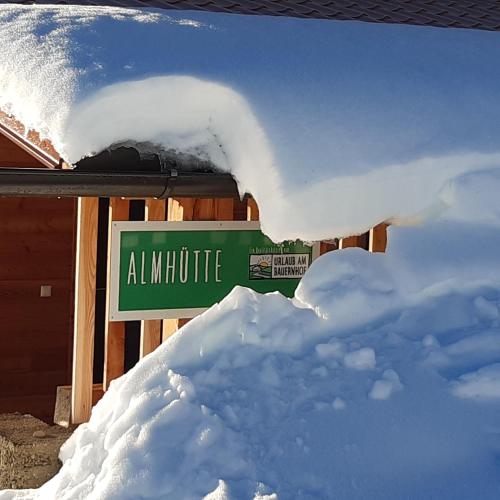 a pile of snow next to a green street sign at Ferienhaus Lärchenhütte in Kasperle