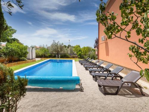 een zwembad met een rij stoelen naast een gebouw bij Villa Ketty in Fažana