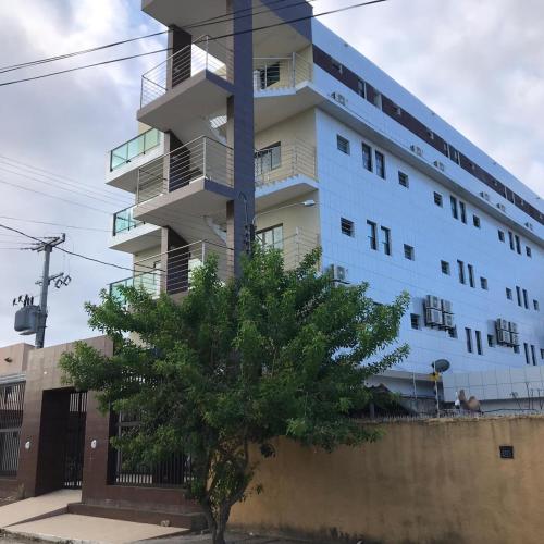 un bâtiment blanc avec un arbre devant lui dans l'établissement Pousada Unique Porto de Galinhas, à Porto de Galinhas