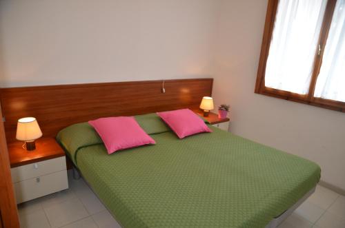 ビビオーネにあるAppartamenti I Moschettieriのベッドルーム1室(緑のベッド1台、ピンクの枕2つ付)
