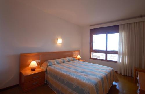 1 dormitorio con 1 cama, 1 ventana y 2 lámparas en LETS HOLIDAYS Beachfront apartment tossa de mar en Tossa de Mar
