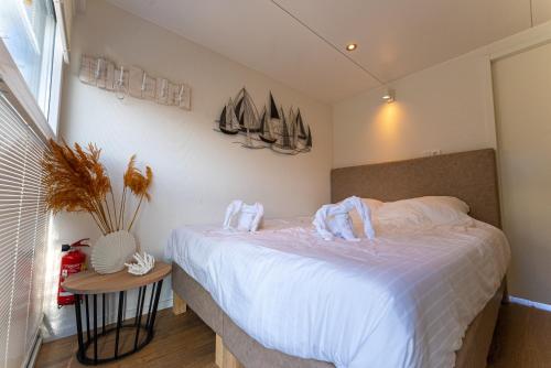a bedroom with a bed with white sheets and boats on the wall at Houseboats Lemmer in Lemmer