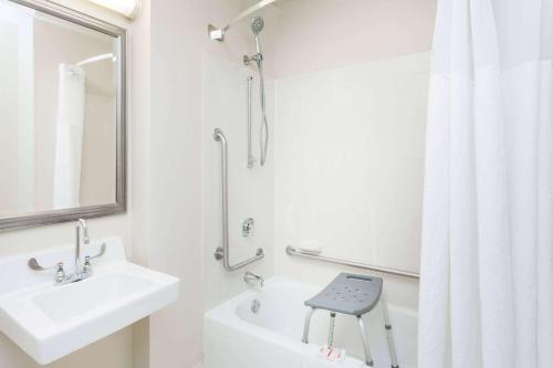 a white bathroom with a sink and a shower at Baymont by Wyndham Peoria in Peoria