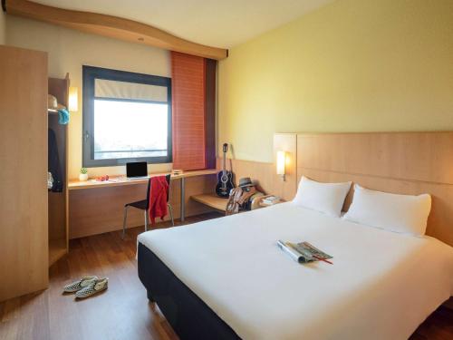 ein Hotelzimmer mit einem großen weißen Bett und einem Schreibtisch in der Unterkunft Hotel Ibis Milano Malpensa in Cardano al Campo