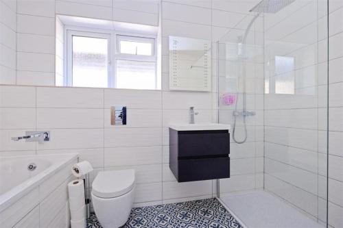 a white bathroom with a toilet and a sink at Stunning family home, walking distance to Herne Bay Beach! in Kent