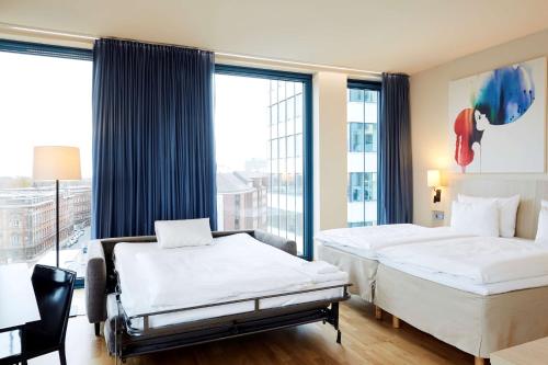 a hotel room with two beds and a large window at Scandic Hamburg Emporio in Hamburg