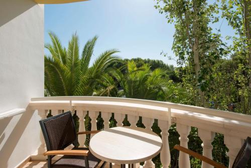 a balcony with a table and chairs and palm trees at Iberostar Selection Albufera Playa All Inclusive in Playa de Muro