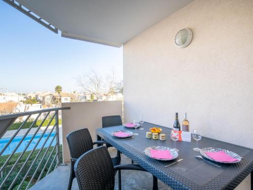 a table with wine bottles and glasses on a balcony at Apartment Les Caraïbes-1 by Interhome in Le Grau-du-Roi