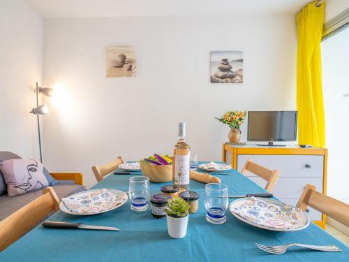 uma mesa com pratos e uma garrafa de vinho em Apartment Jamaïc by Interhome em La Grande-Motte