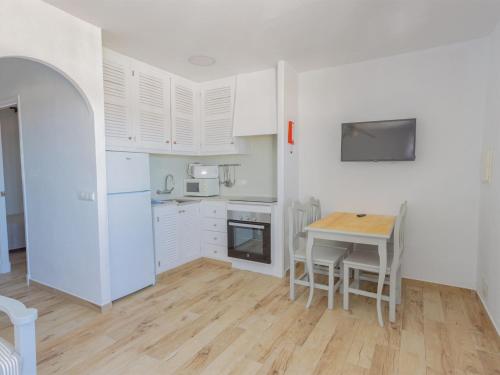 una cocina con armarios blancos y una mesa con sillas. en Apartment Son Bou Gardens Apt 2 dorm by Interhome, en Son Bou