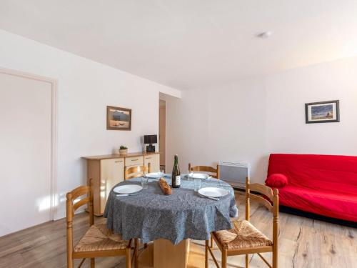- un salon avec une table, des chaises et un canapé rouge dans l'établissement Apartment Le Petit Robinson-1 by Interhome, à La Richardais