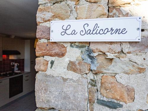 Ein Schild, auf dem la salerno an einer Steinmauer steht. in der Unterkunft Holiday Home La salicorne by Interhome in Pirou