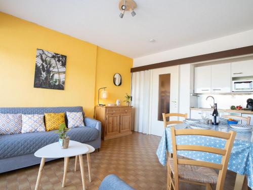 ein Wohnzimmer mit einem blauen Sofa und einer Küche in der Unterkunft Studio Le Cormoran-5 by Interhome in Le Grau-du-Roi