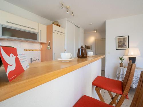 une cuisine avec un comptoir et une chaise rouge dans l'établissement Apartment L'Hyppocampe by Interhome, au Grau-du-Roi