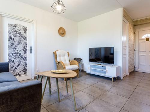 a living room with a couch and a table and a tv at Holiday Home Le Coquelicot by Interhome in Pirou
