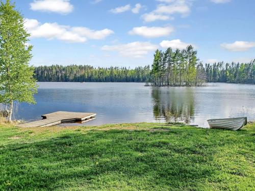 a lake with a dock and a boat in the grass at Holiday Home Villa niemi by Interhome in Kotalahti