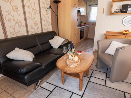 a living room with a black leather couch and a table at Holiday Home Siggi by Interhome in Norddeich