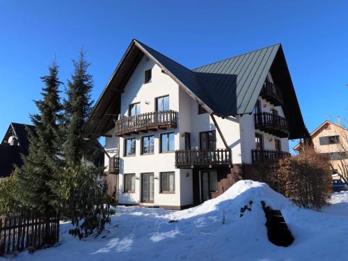 a white house with a black roof in the snow at Apartment Alice II- by Interhome in Harrachov