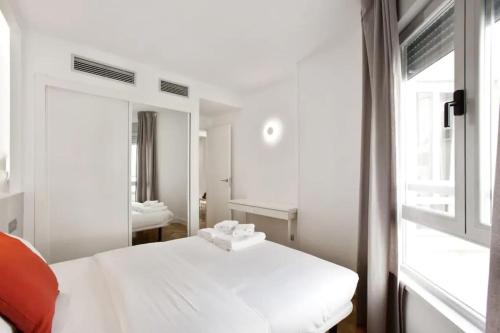 - une chambre avec un lit blanc et un miroir dans l'établissement Apar. renovado en Leganitos (Gran Vía) con portero, à Madrid