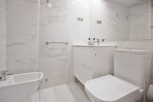 a white bathroom with a toilet and a sink at Apar. renovado en Leganitos (Gran Vía) con portero in Madrid