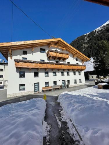a large white building with snow in front of it at APART Kirschner in Sankt Leonhard im Pitztal