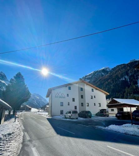 a building on the side of a road with mountains at APART Kirschner in Sankt Leonhard im Pitztal