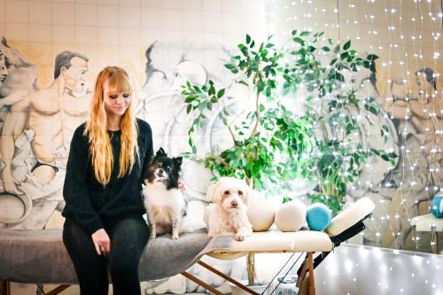 a woman sitting on a bench with two dogs at Berghotel Steiger - Erzgebirge in Schneeberg