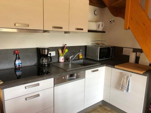 a kitchen with white cabinets and a sink and a microwave at Chalet LE TREMPLIN, 4 à 5 pers, XONRUPT-LONGEMER in Xonrupt-Longemer