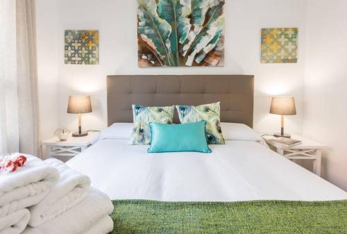 a bedroom with a large white bed with blue pillows at Apartamento con jardin privado in Madrid