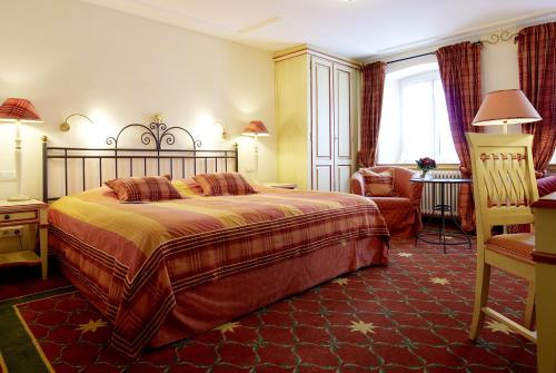 a bedroom with a large bed and a chair at Hotel & Restaurant Sonne in Kirchzarten