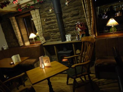 una mesa y sillas en una habitación con chimenea en The Anchor Inn en Whittonstall